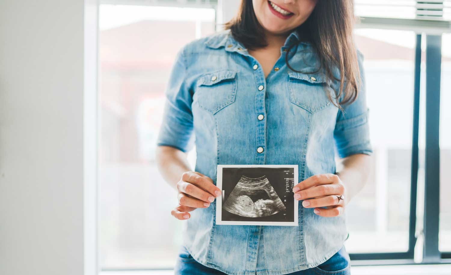 mother holding ultrasound photo
