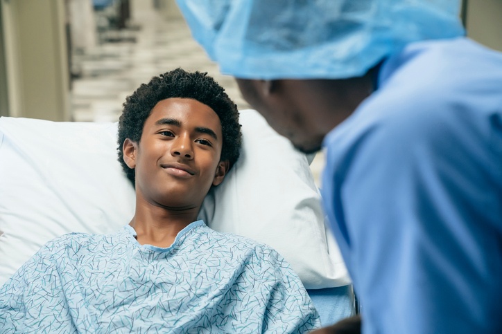 Male nurse talking to young male hospital patient about to have surgery